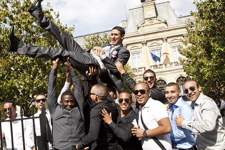 Les amis lancent le marié en l'air devant la mairie